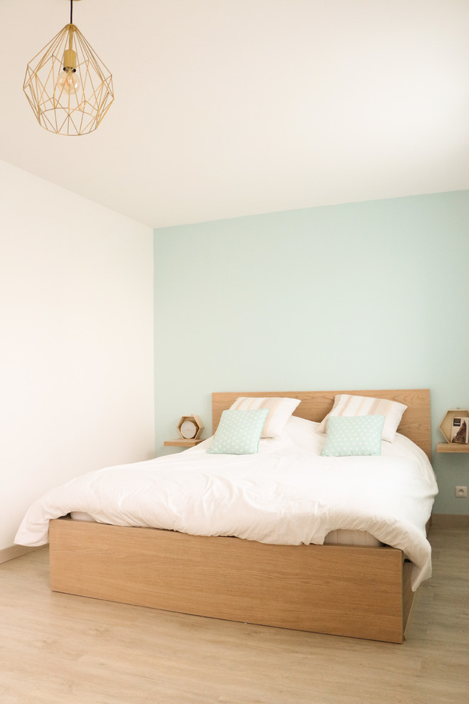 Idée de décoration pour une chambre parentale blanche et bois nordique de taille moyenne avec parquet clair et un mur bleu.