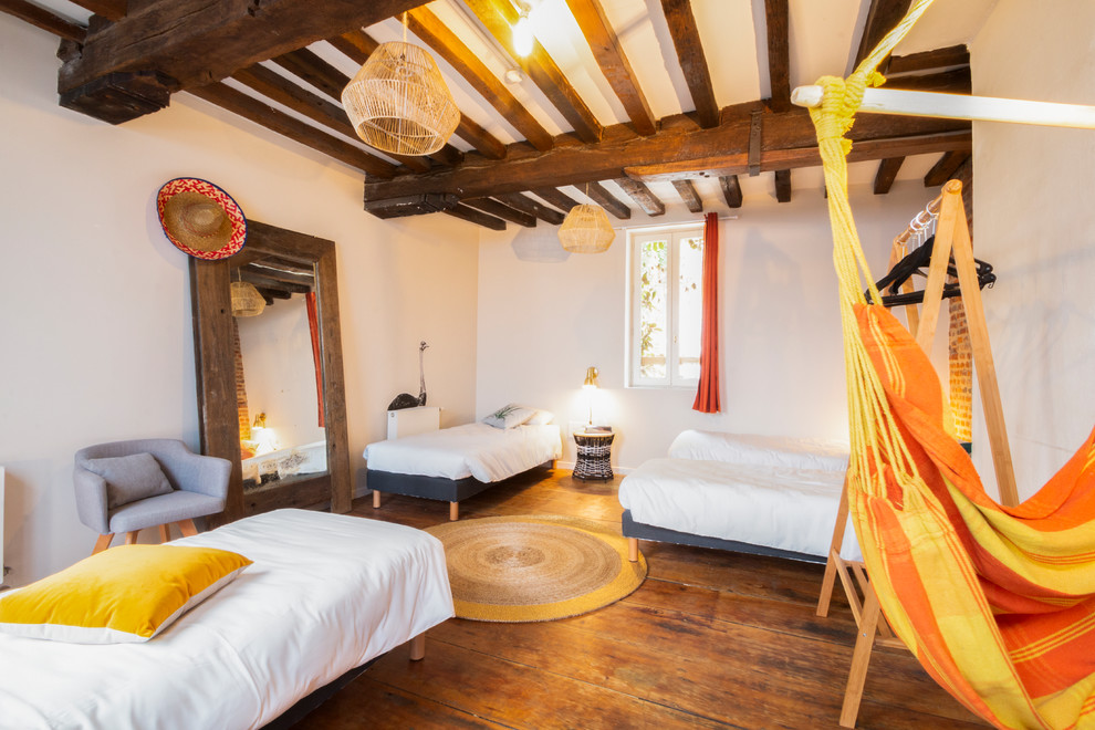 Modelo de dormitorio principal bohemio con paredes blancas, suelo de madera en tonos medios y suelo marrón