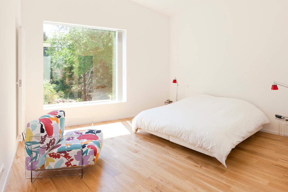 Idée de décoration pour une grande chambre d'amis design avec un mur blanc et un sol en bois brun.