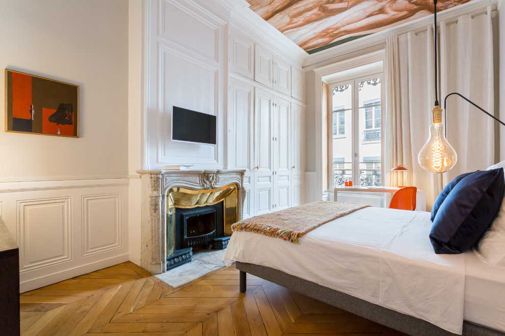 На фото: хозяйская спальня в стиле фьюжн с белыми стенами, паркетным полом среднего тона, стандартным камином и коричневым полом с