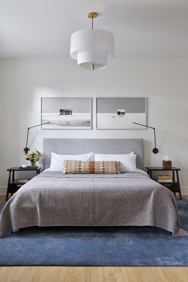 Modernes Schlafzimmer ohne Kamin mit weißer Wandfarbe und hellem Holzboden in New York