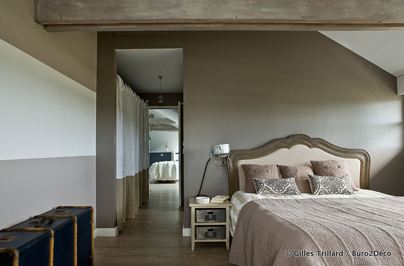 Cette image montre une grande chambre d'amis bohème avec un mur beige, parquet clair et un sol marron.