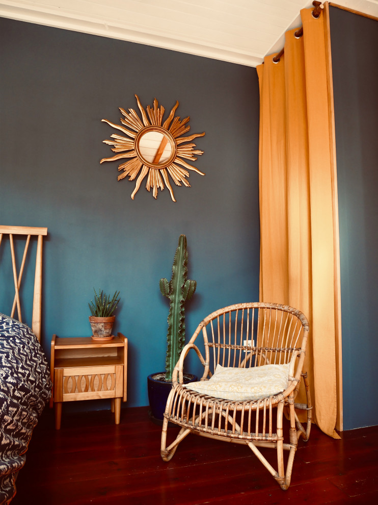 Cette photo montre une chambre parentale rétro avec un mur bleu, parquet foncé et un sol marron.