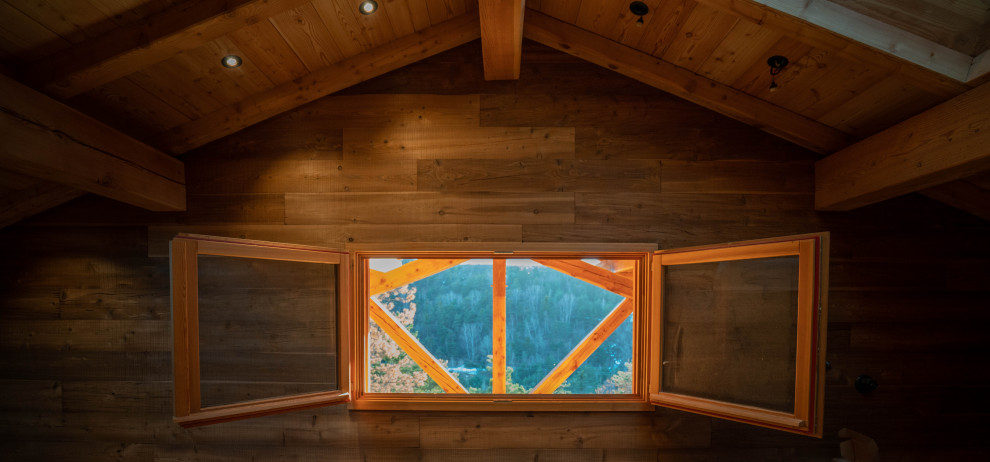 Example of a mountain style medium tone wood floor and wood wall bedroom design in Other