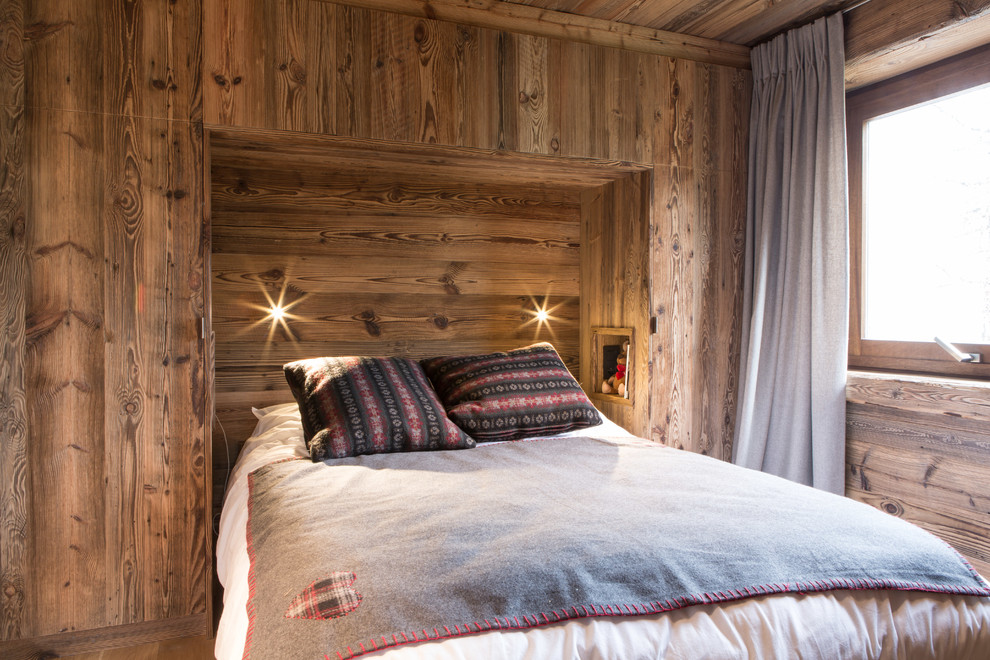На фото: хозяйская спальня среднего размера в стиле рустика с коричневыми стенами без камина с