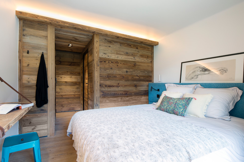 Imagen de dormitorio principal rústico de tamaño medio sin chimenea con paredes blancas y suelo de madera en tonos medios