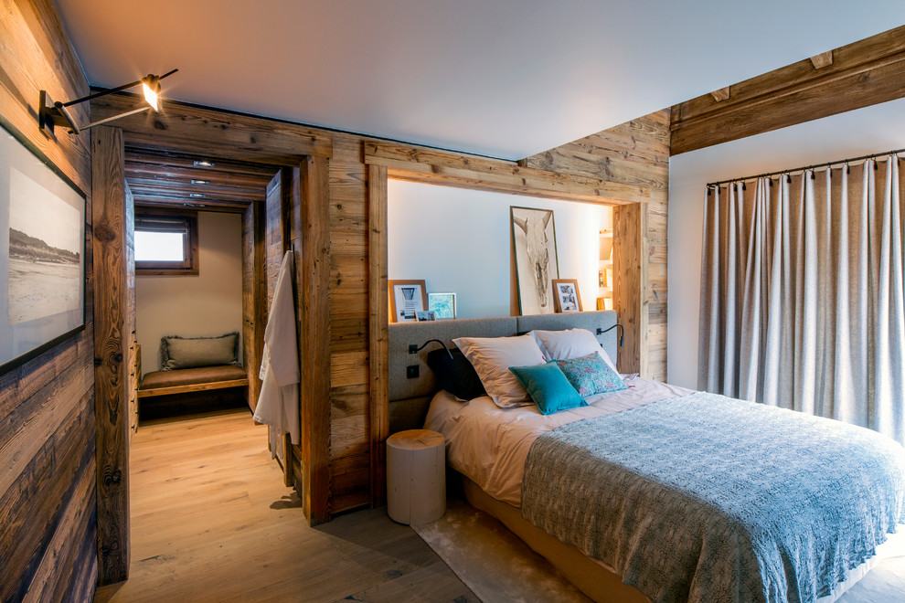 Diseño de dormitorio principal rural de tamaño medio sin chimenea con paredes blancas y suelo de madera en tonos medios