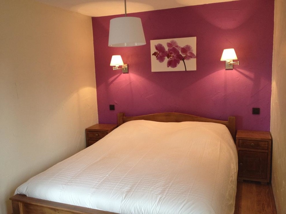 Idée de décoration pour une chambre parentale chalet de taille moyenne avec un mur rose, un sol en bois brun et un sol marron.