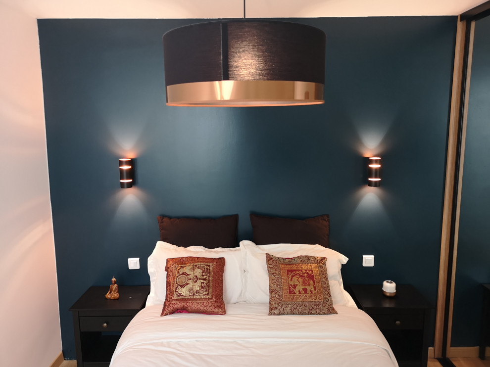 Cette image montre une chambre parentale minimaliste de taille moyenne avec un mur bleu, parquet clair et un sol marron.