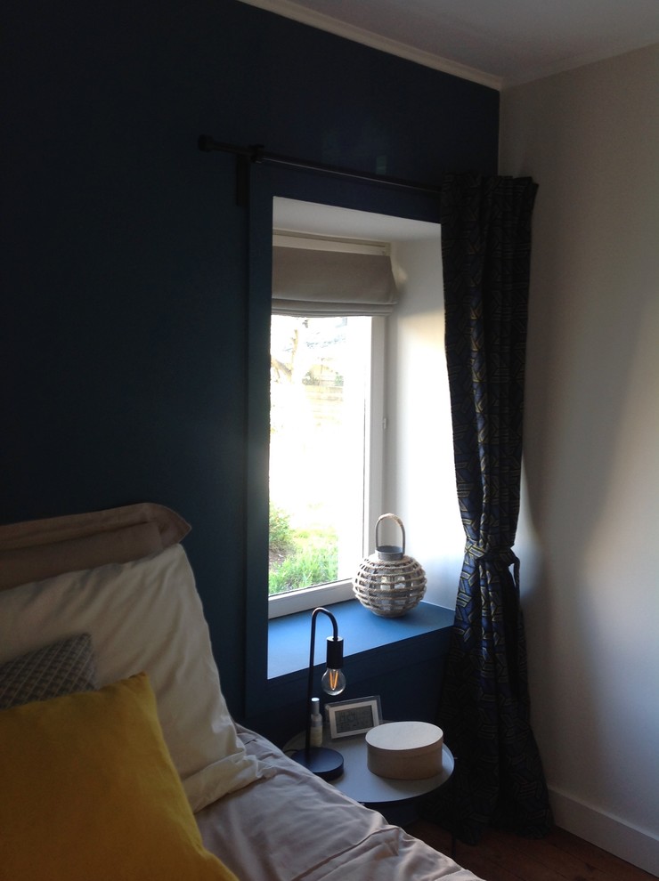 Inspiration pour une petite chambre parentale design avec un mur bleu, un sol en bois brun et un sol marron.