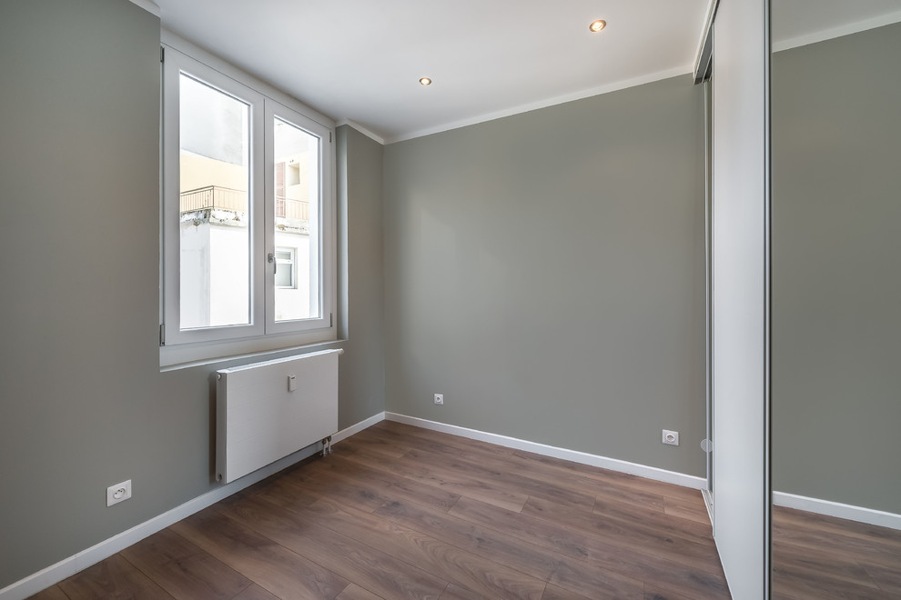 Idée de décoration pour une petite chambre parentale minimaliste avec un mur vert et un sol en bois brun.