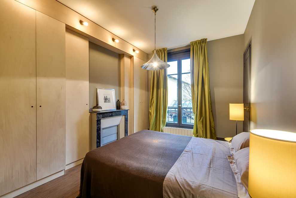 Mittelgroßes Modernes Hauptschlafzimmer mit braunem Holzboden und Kamin in Paris