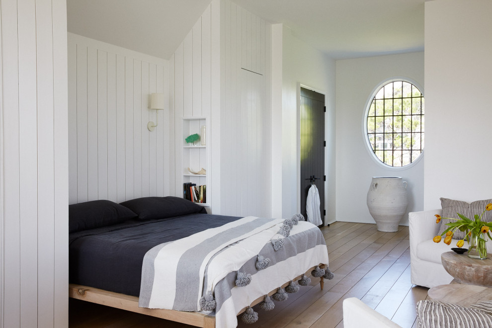 他の地域にある広い地中海スタイルのおしゃれな寝室 (白い壁、淡色無垢フローリング、ベージュの床、塗装板張りの壁)