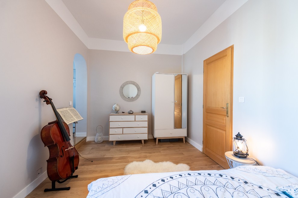 Ejemplo de dormitorio escandinavo grande sin chimenea con paredes beige, suelo de madera clara y suelo beige