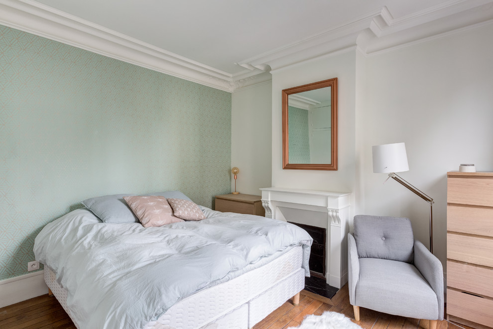 パリにある中くらいな北欧スタイルのおしゃれな主寝室 (緑の壁、無垢フローリング、標準型暖炉、漆喰の暖炉まわり、茶色い床)