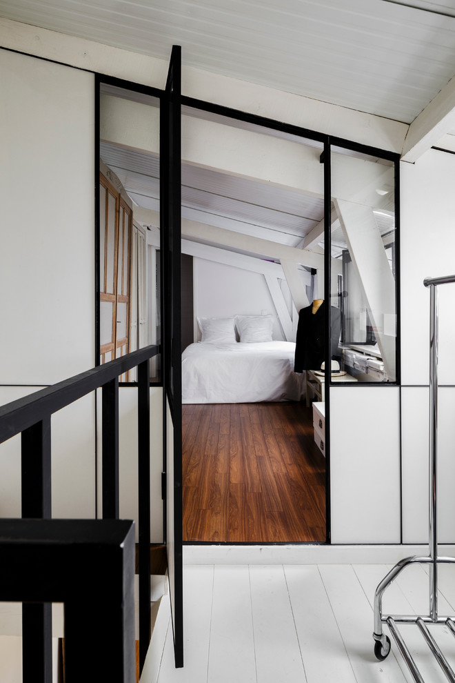 Mittelgroßes Industrial Hauptschlafzimmer ohne Kamin mit weißer Wandfarbe und dunklem Holzboden in Paris