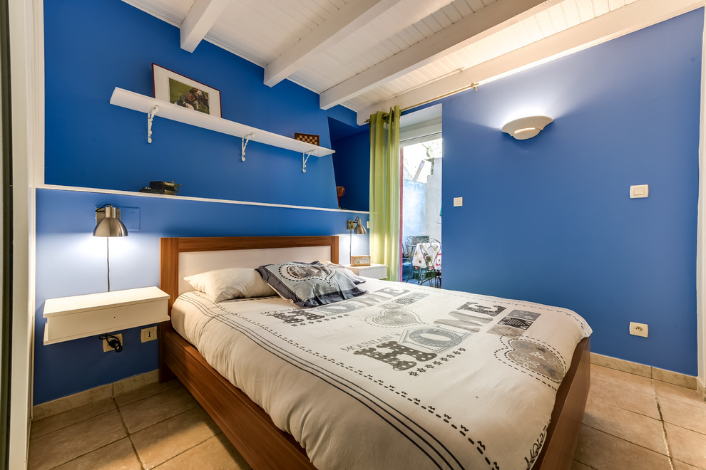 Réalisation d'une petite chambre parentale design avec un mur bleu, un sol en carrelage de céramique et un sol beige.
