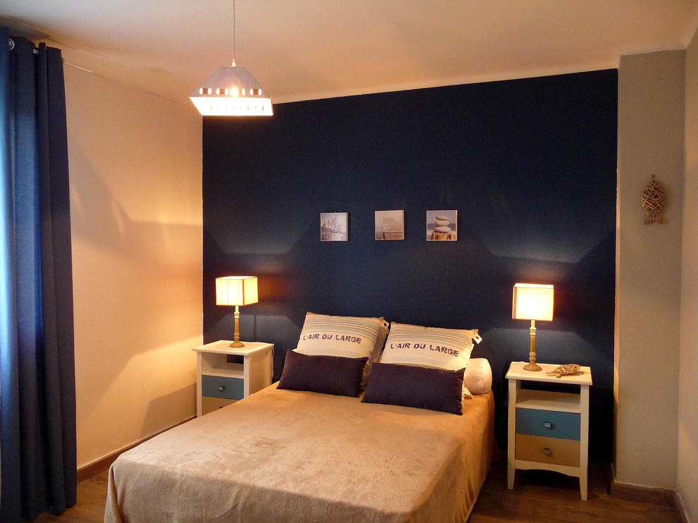 Imagen de dormitorio principal costero de tamaño medio sin chimenea con paredes azules, suelo vinílico y suelo marrón