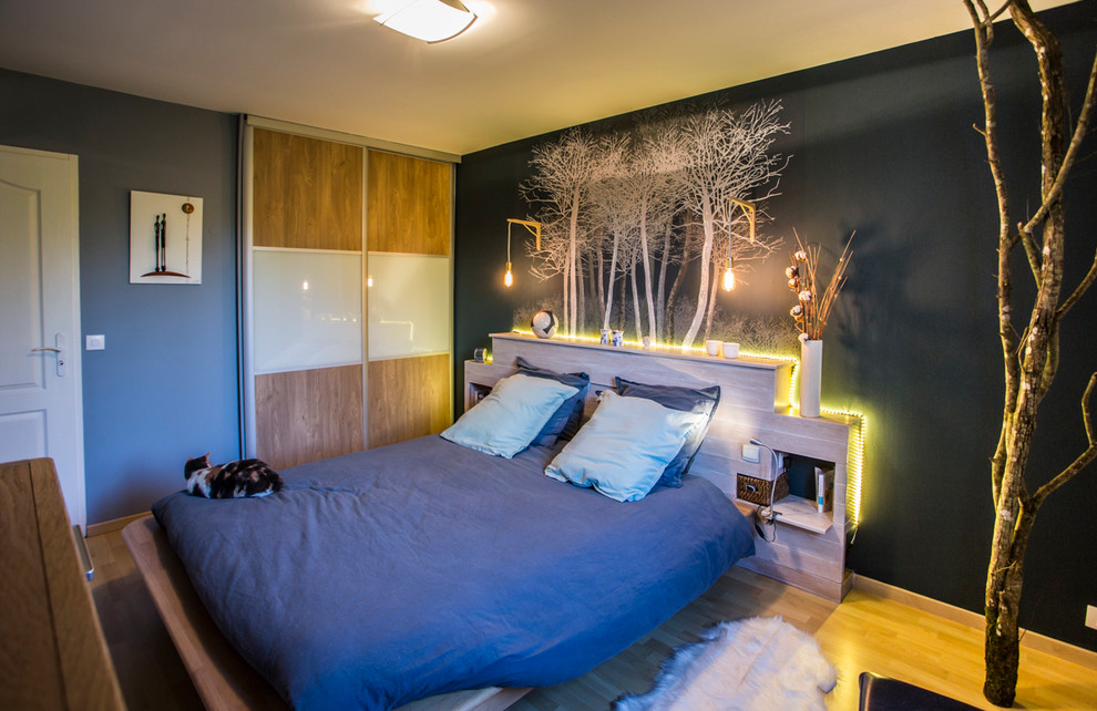 Idée de décoration pour une chambre parentale nordique de taille moyenne avec un mur bleu, parquet clair et aucune cheminée.