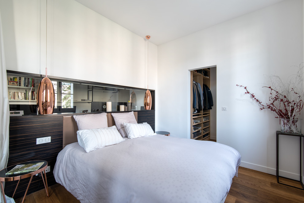Diseño de dormitorio principal de tamaño medio sin chimenea con paredes blancas, suelo de madera oscura y suelo marrón