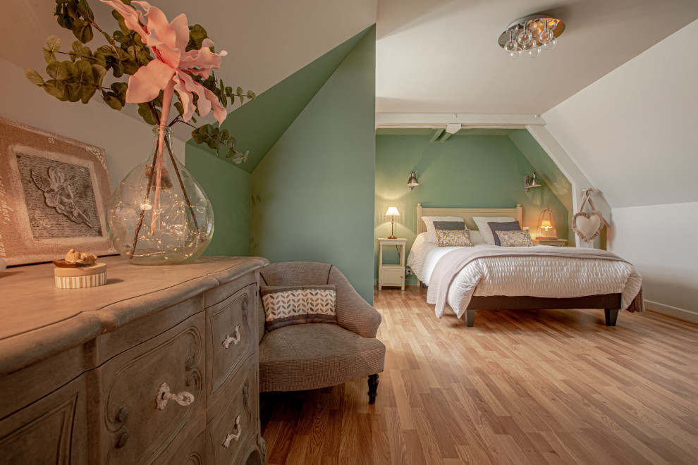 На фото: гостевая спальня среднего размера, (комната для гостей) в стиле неоклассика (современная классика) с зелеными стенами, полом из ламината и коричневым полом без камина с