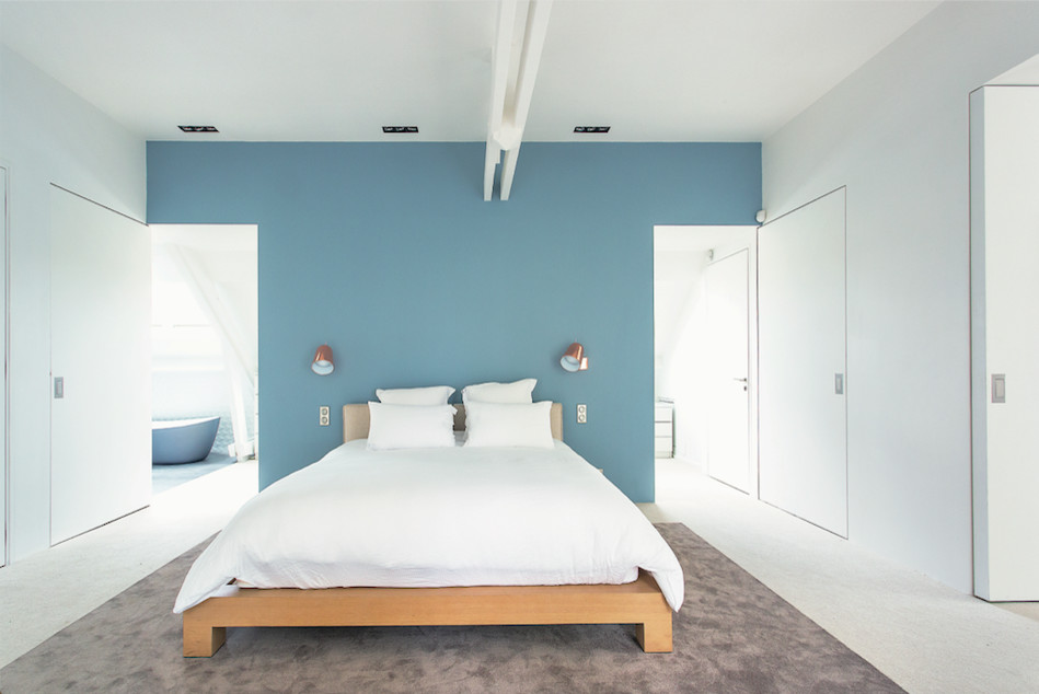 Ispirazione per una camera matrimoniale minimalista con pareti blu, moquette e pavimento beige