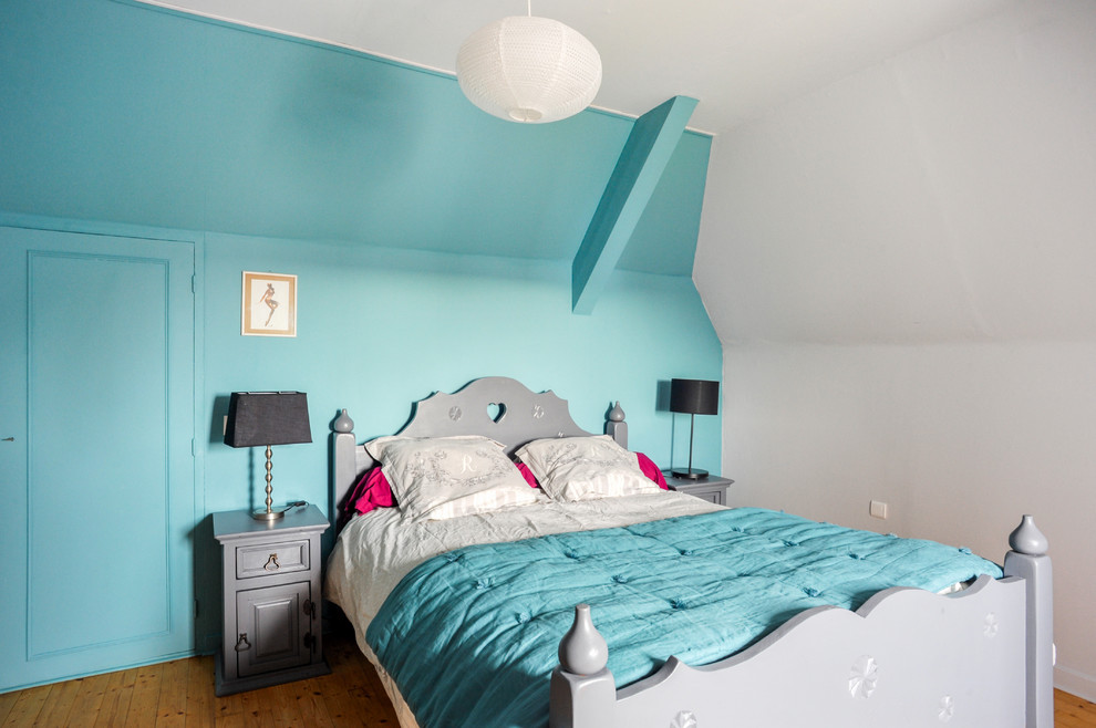 Diseño de dormitorio tipo loft costero de tamaño medio sin chimenea con paredes azules, suelo de madera clara y suelo beige