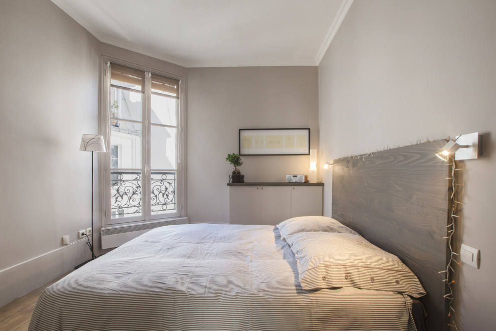 Medium sized contemporary master bedroom in Paris with beige walls and medium hardwood flooring.
