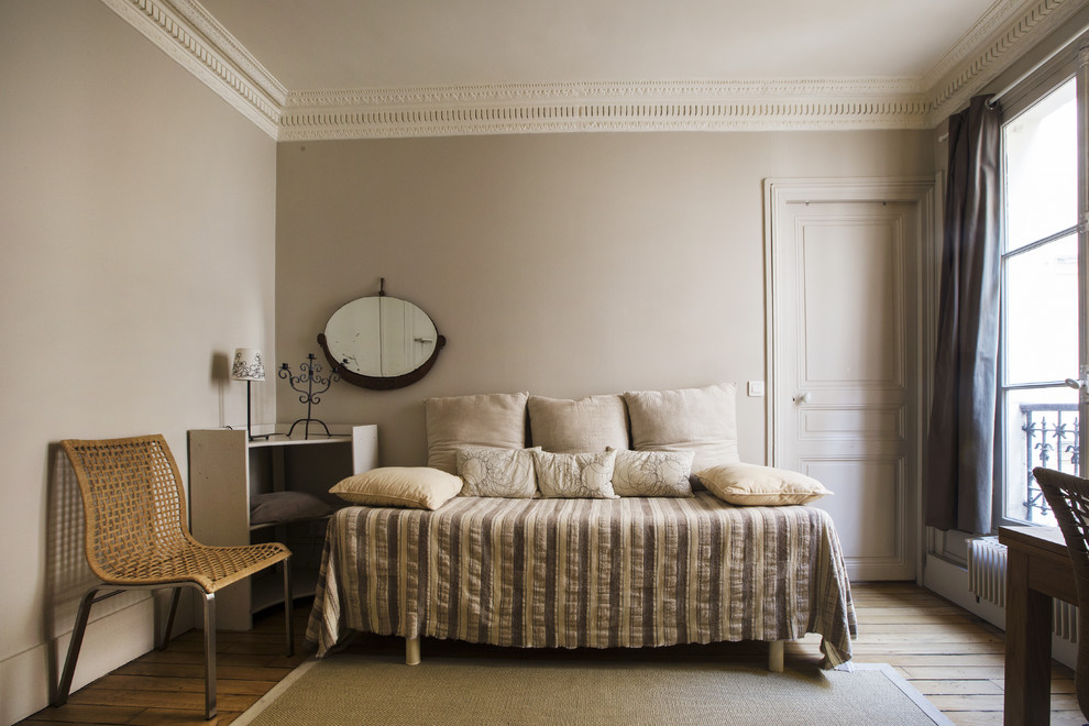 Example of a mid-sized trendy guest medium tone wood floor bedroom design in Paris with beige walls