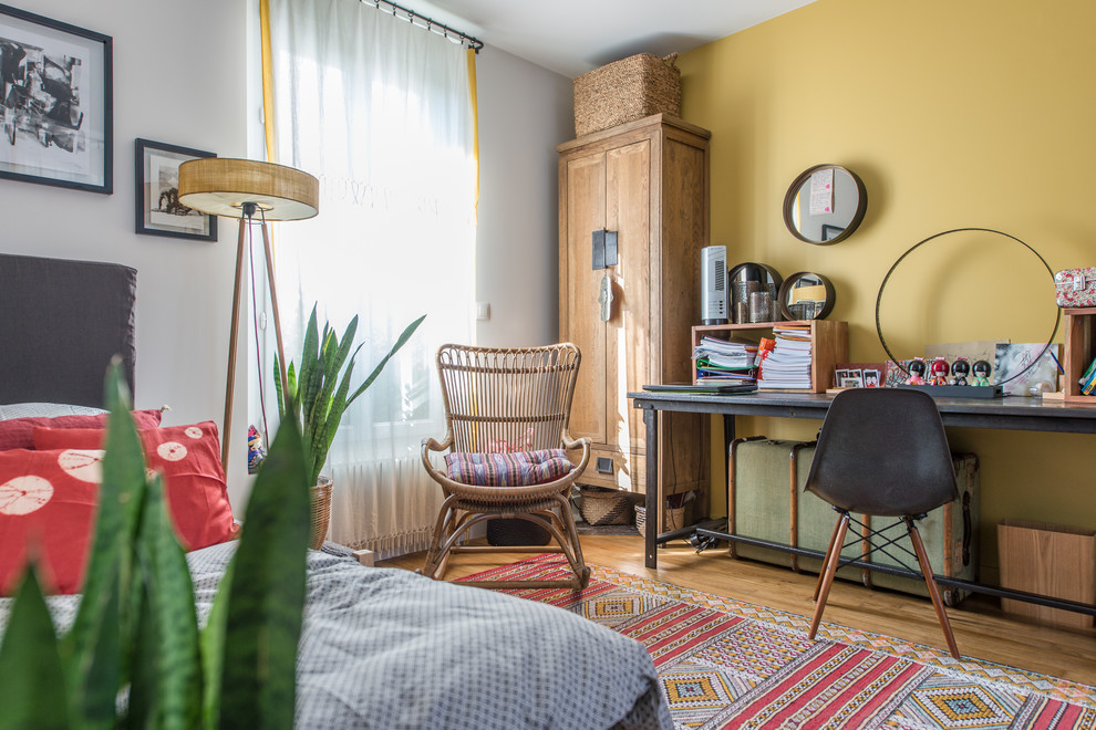 Cette photo montre une chambre éclectique avec un mur jaune, un sol en bois brun et un sol marron.