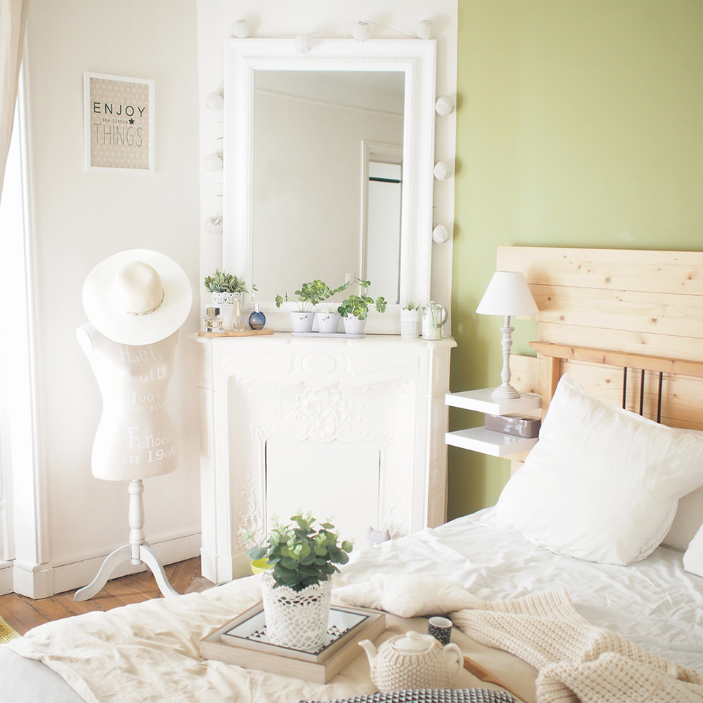 Imagen de dormitorio principal romántico de tamaño medio con paredes verdes, suelo de madera clara y chimenea de esquina