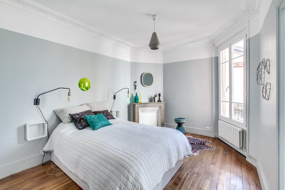 Inspiration för klassiska sovrum, med blå väggar, mellanmörkt trägolv och en standard öppen spis