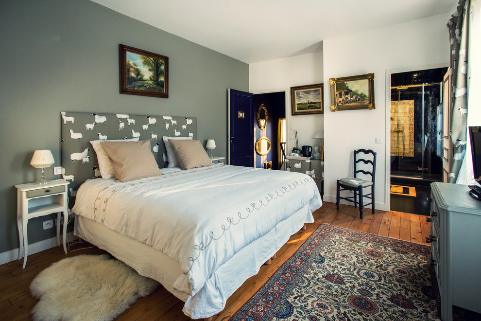 This is an example of a medium sized bohemian master bedroom in Paris with grey walls and medium hardwood flooring.