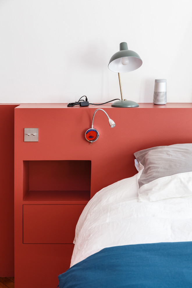 Diseño de dormitorio principal minimalista grande sin chimenea con paredes rojas, suelo de madera en tonos medios y suelo marrón