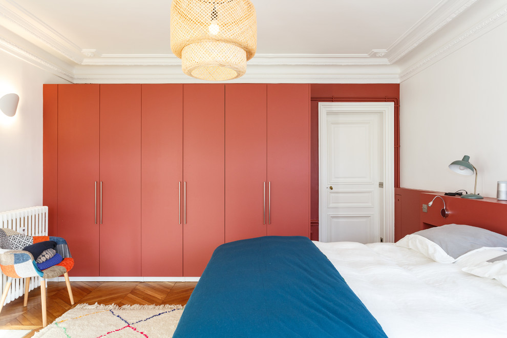 ロンドンにある広いモダンスタイルのおしゃれな主寝室 (赤い壁、無垢フローリング、暖炉なし、茶色い床) のインテリア