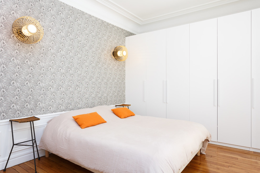 Immagine di una camera matrimoniale minimalista di medie dimensioni con pareti multicolore, pavimento in legno massello medio, nessun camino e pavimento marrone