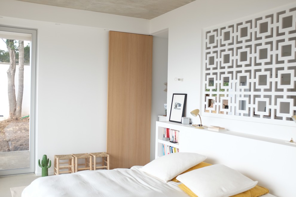 Cette photo montre une chambre d'amis tendance de taille moyenne avec un mur blanc et un sol gris.