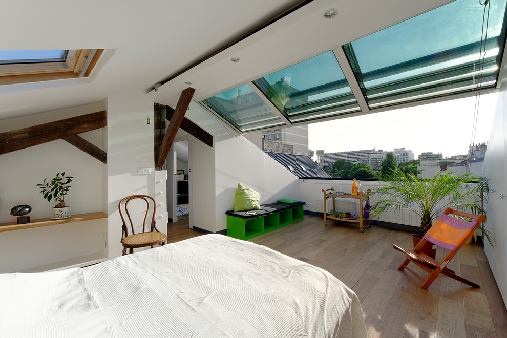 Design ideas for a contemporary loft bedroom in Paris with white walls and light hardwood flooring.
