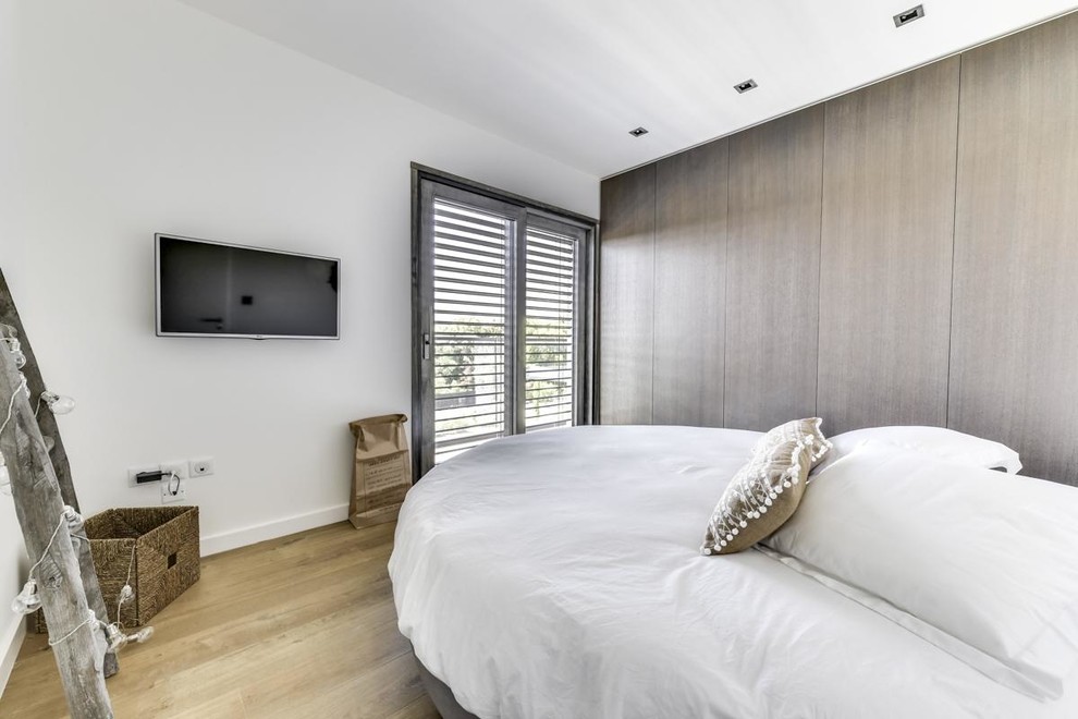 Design ideas for a contemporary bedroom in Montpellier with white walls, light hardwood flooring and beige floors.