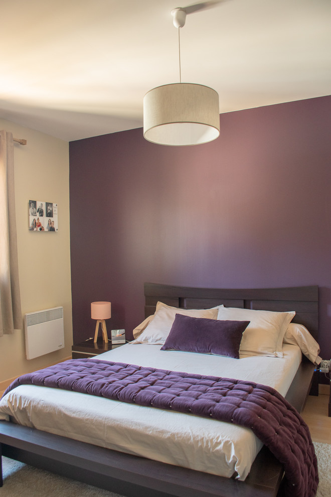Cette photo montre une grande chambre parentale tendance avec un mur violet, un sol beige et sol en stratifié.