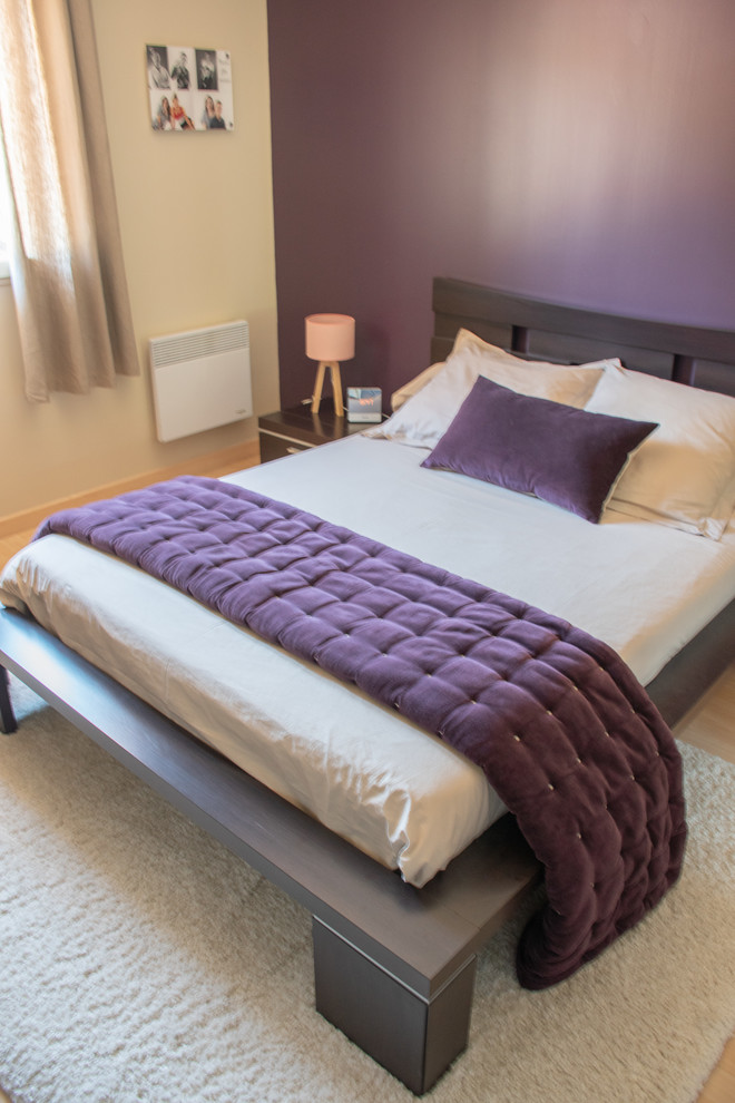 This is an example of a large contemporary master bedroom in Lyon with purple walls, beige floors and laminate floors.