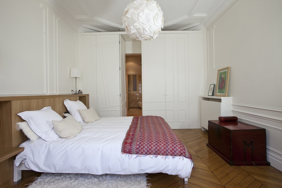 Idée de décoration pour une chambre tradition avec un mur blanc, un sol en bois brun et un sol marron.