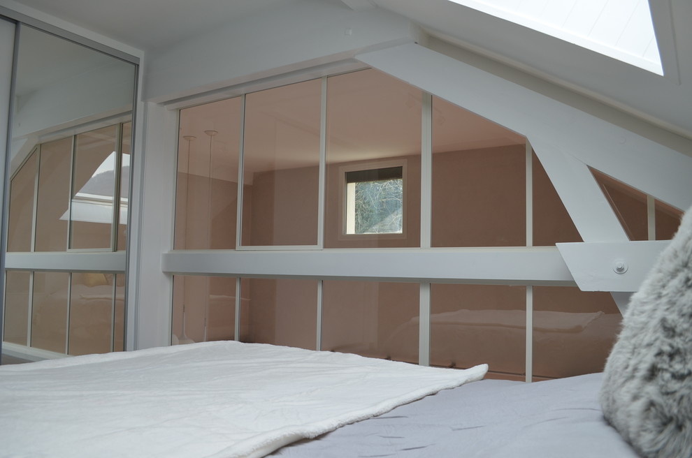 Modelo de dormitorio principal actual de tamaño medio sin chimenea con paredes blancas, suelo laminado y suelo gris
