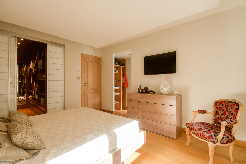 Aménagement d'une chambre parentale contemporaine de taille moyenne avec un mur beige et parquet clair.