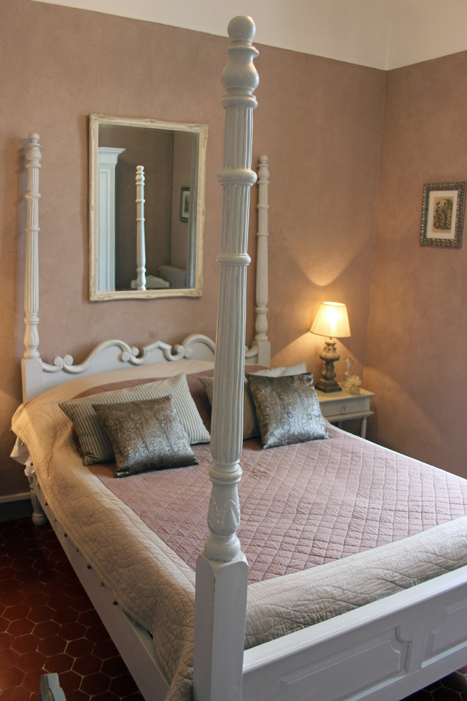 На фото: хозяйская спальня среднего размера в классическом стиле с розовыми стенами, полом из терракотовой плитки и коричневым полом без камина