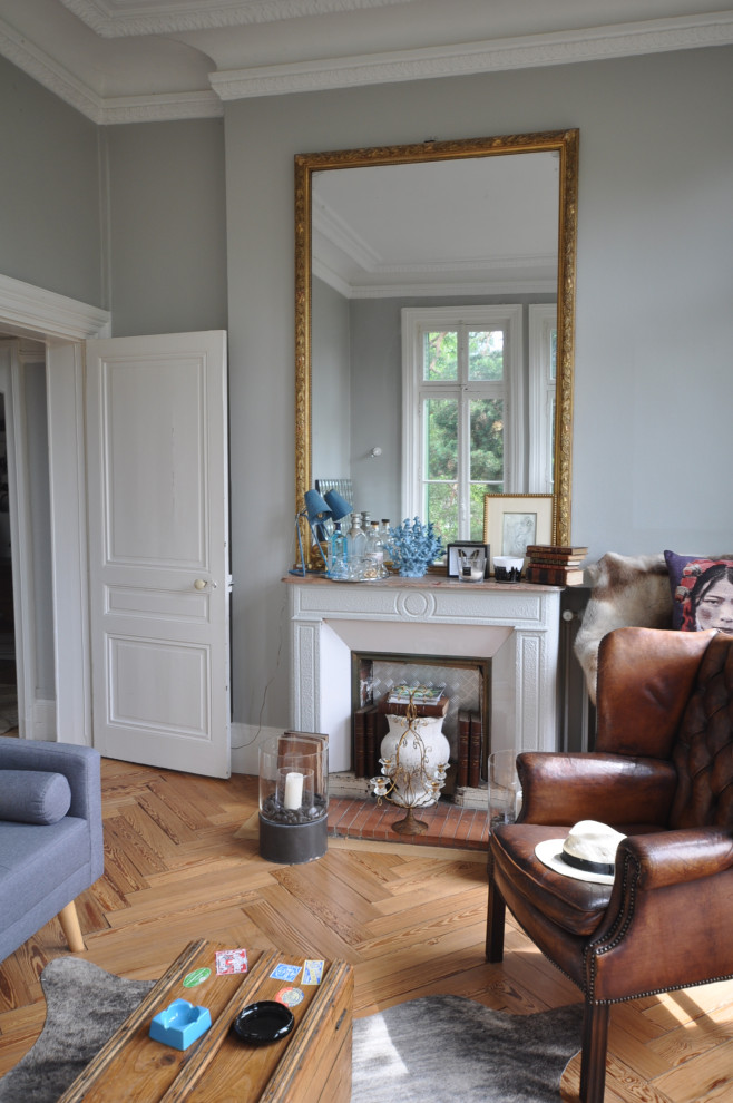 Mittelgroßes Stilmix Schlafzimmer im Loft-Style mit grauer Wandfarbe, dunklem Holzboden, Kamin, Kaminumrandung aus Backstein und braunem Boden in Lyon