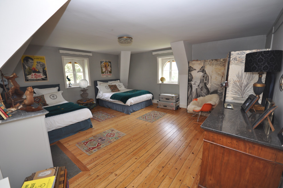 Mittelgroßes Retro Schlafzimmer im Loft-Style mit grauer Wandfarbe, dunklem Holzboden, Kamin, Kaminumrandung aus Backstein und braunem Boden in Lyon
