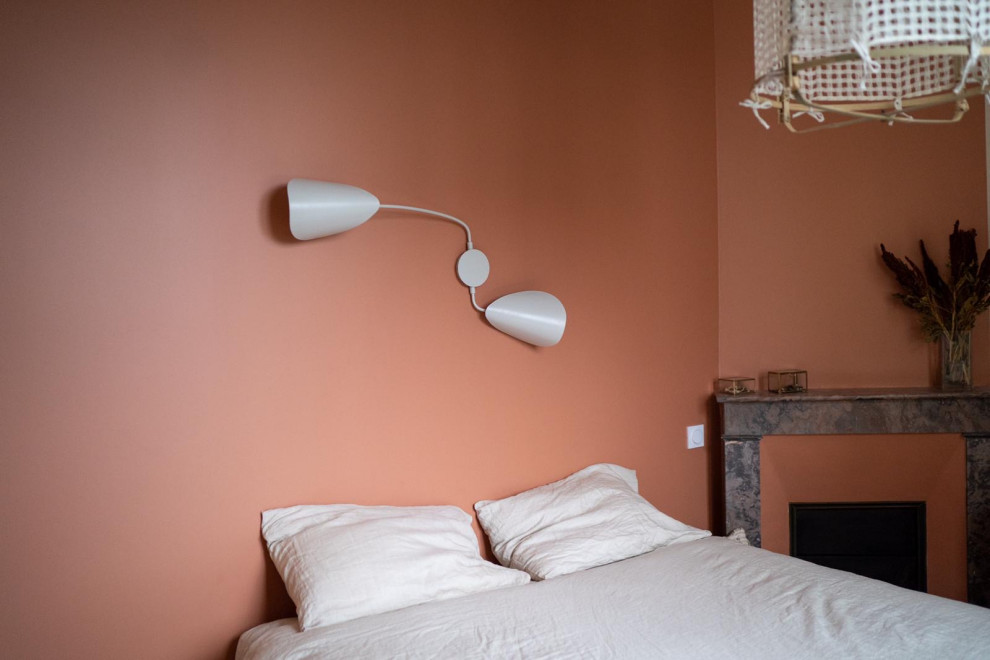 ルアーブルにある小さなコンテンポラリースタイルのおしゃれな客用寝室 (オレンジの壁、淡色無垢フローリング、コーナー設置型暖炉、石材の暖炉まわり) のインテリア