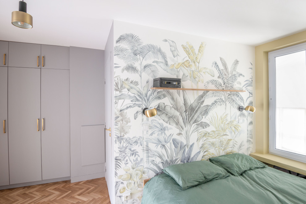 Modelo de dormitorio actual con paredes beige, suelo de madera clara y papel pintado