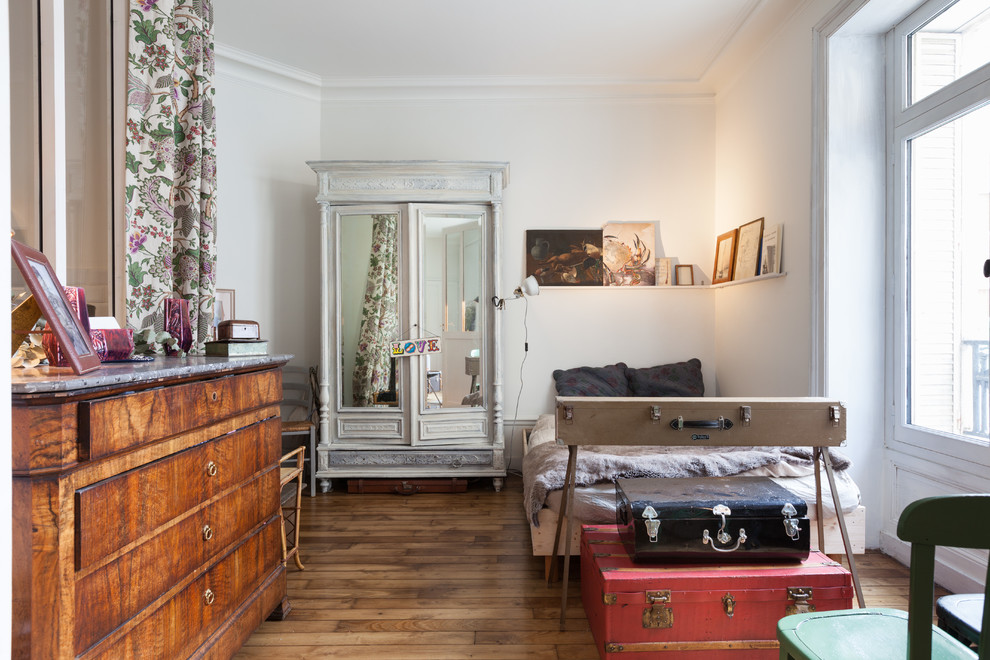 Cette photo montre une chambre éclectique avec un mur blanc et un sol en bois brun.